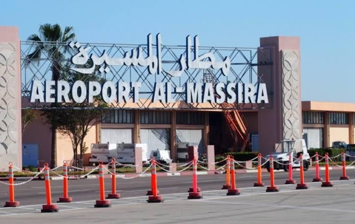 Chauffeur professionnel accueillant un client avec une pancarte nominative à l'aéroport de Marrakech